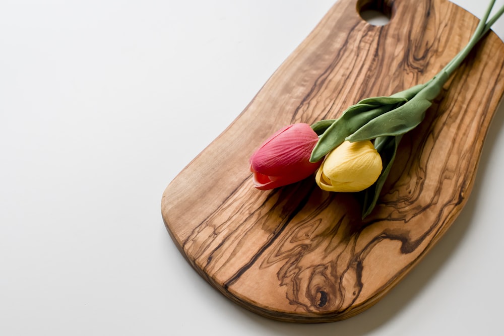 red and yellow tulips on brown wooden chopping board