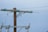 A wooden utility pole supports metal cross arms with glass insulators attached, holding up several taut power lines against a clear blue sky. The structure appears sturdy with electrical components visible at various points.