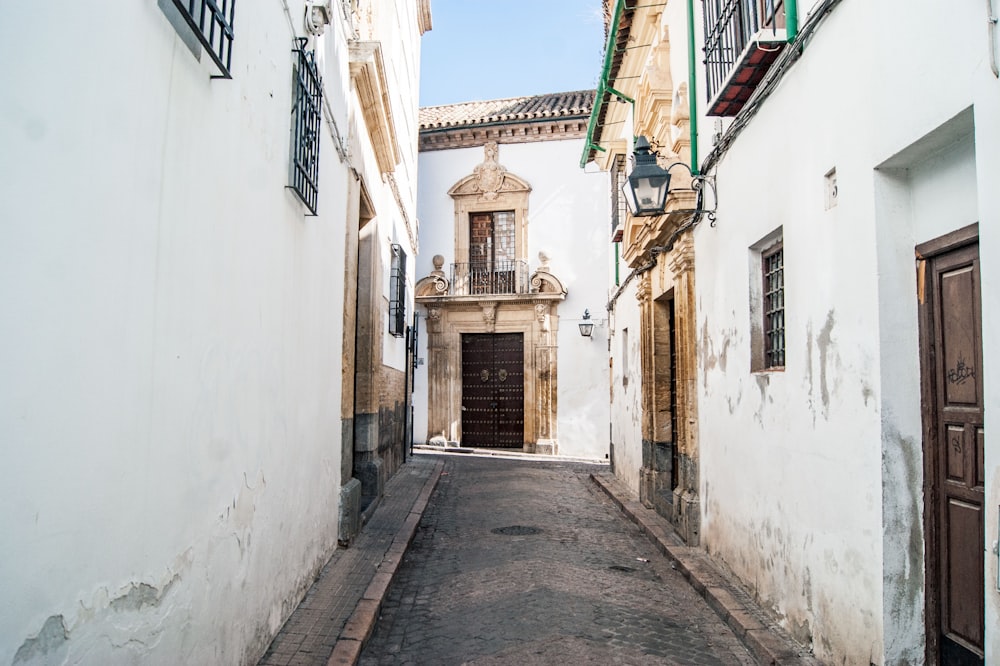 empty street between white concrete houses during daytime