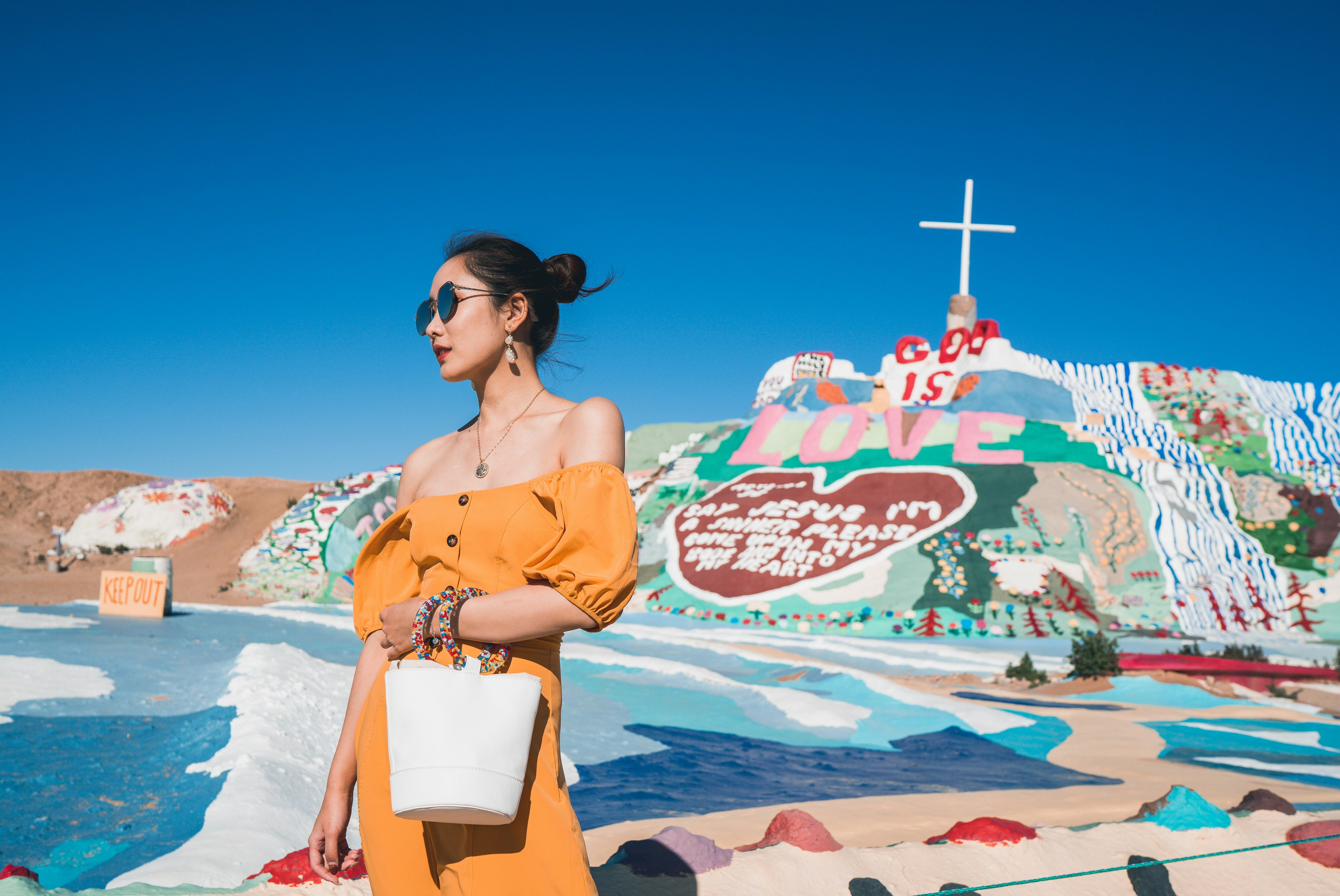 woman in brown dress holding white paper bag standing on beach during daytime