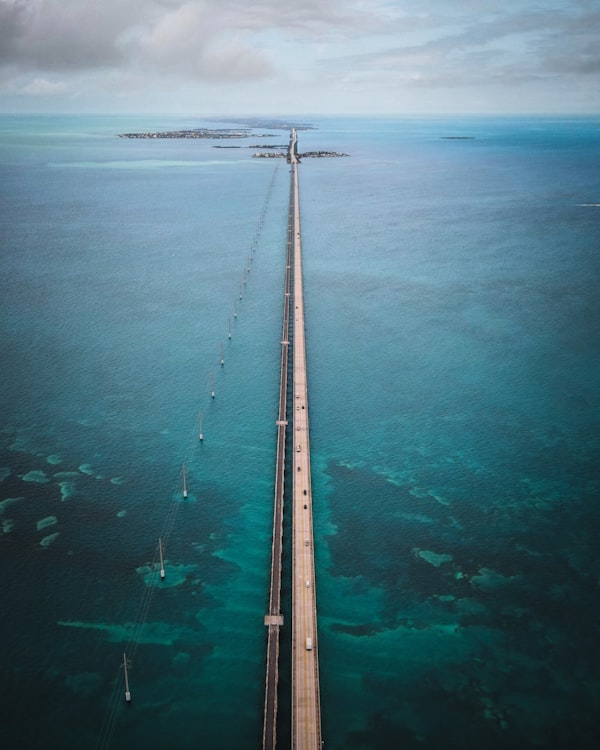 Wooden dock stretching into calm turquoise waters under clear blue sky in the Florida Keys