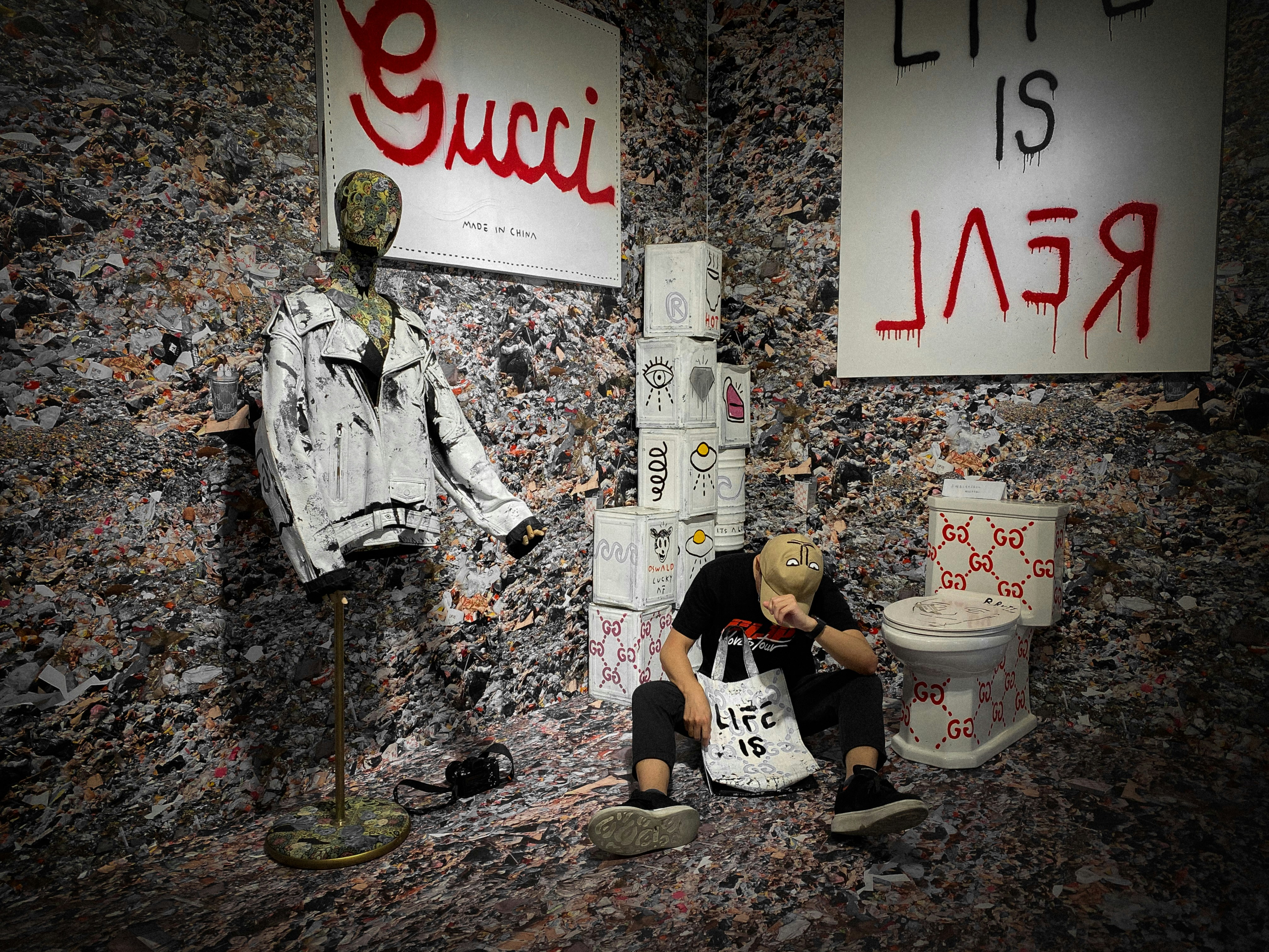 青のデニムジャケットと黒のズボンを着た男が白と赤の愛のプリントの壁のそばに立っています