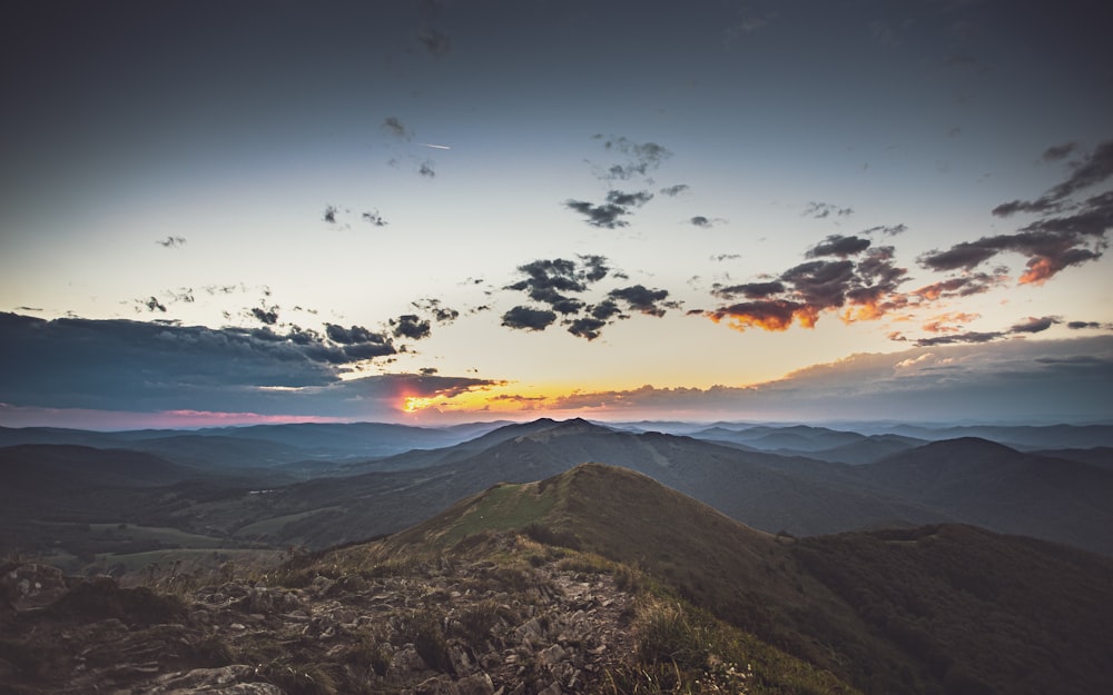 birds flying over the mountains during sunset