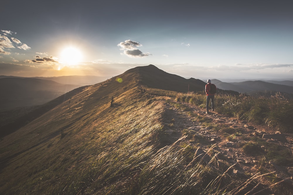 person in black jacket and black pants standing on brown mountain during daytime