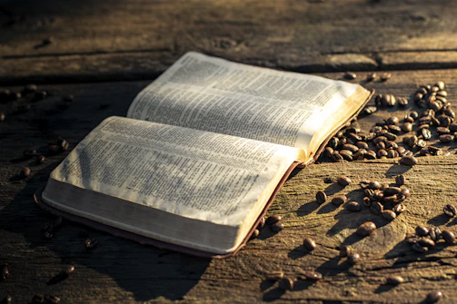 An open ebook with coffee beans scattered around on a marble countertop.