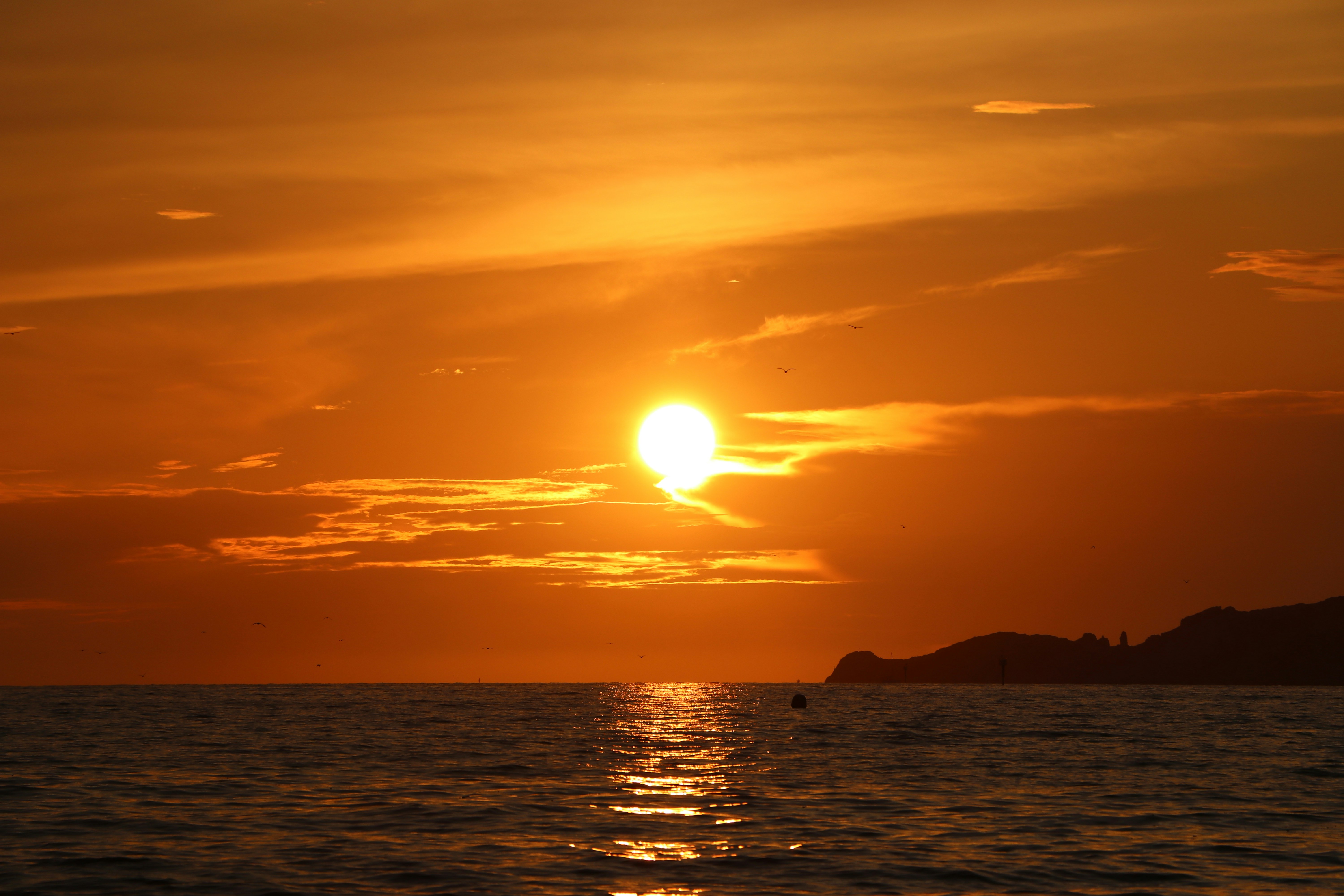 silhouette of mountain beside sea during sunset, 
