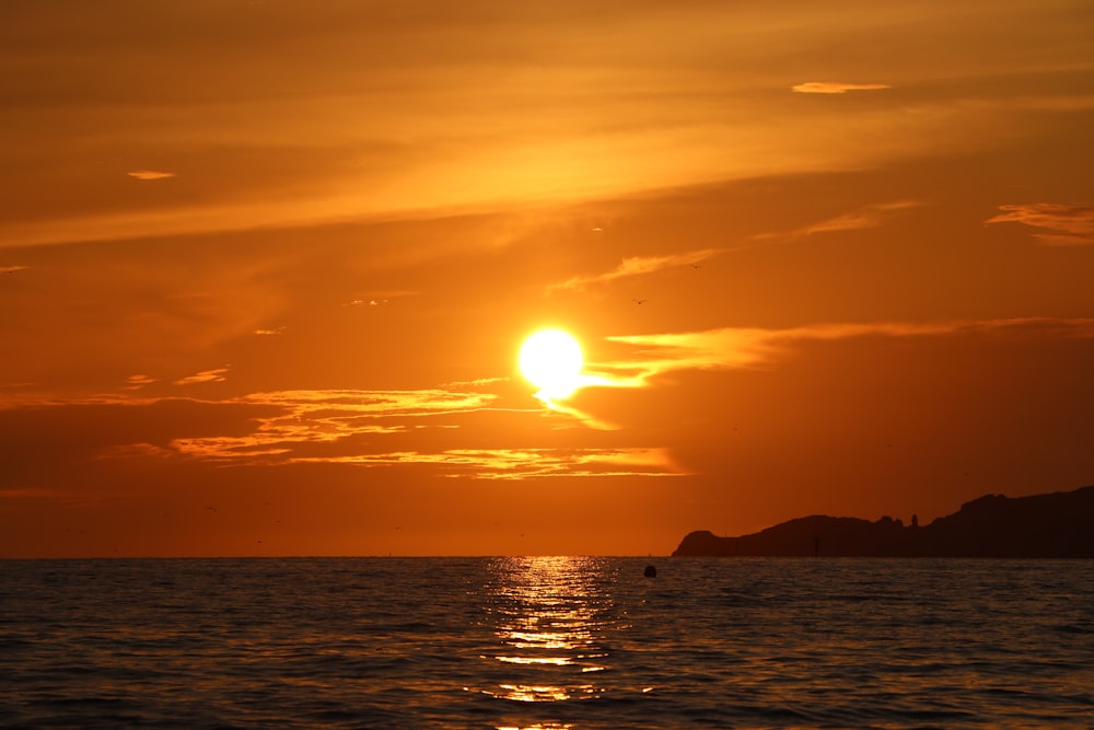 silhouette of mountain beside sea during sunset