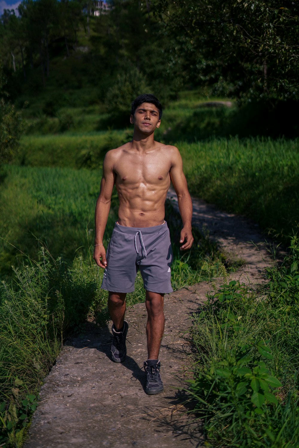 topless man in green shorts standing on green grass field during daytime