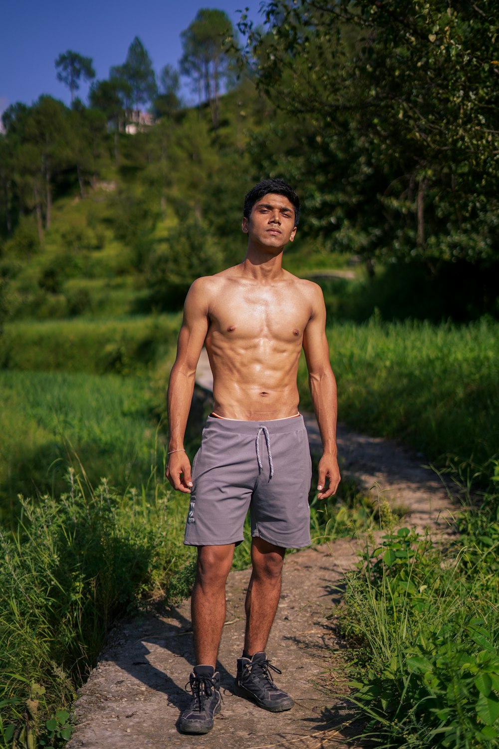 topless man in gray shorts standing on green grass field during daytime