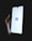 A hand holding a smartphone with a brightly lit screen displaying the Facebook logo in the center.