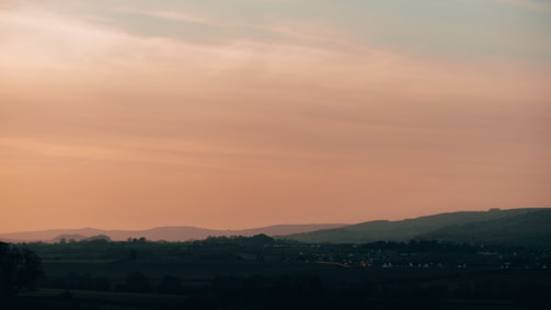 A serene landscape featuring rolling hills at sunset.
