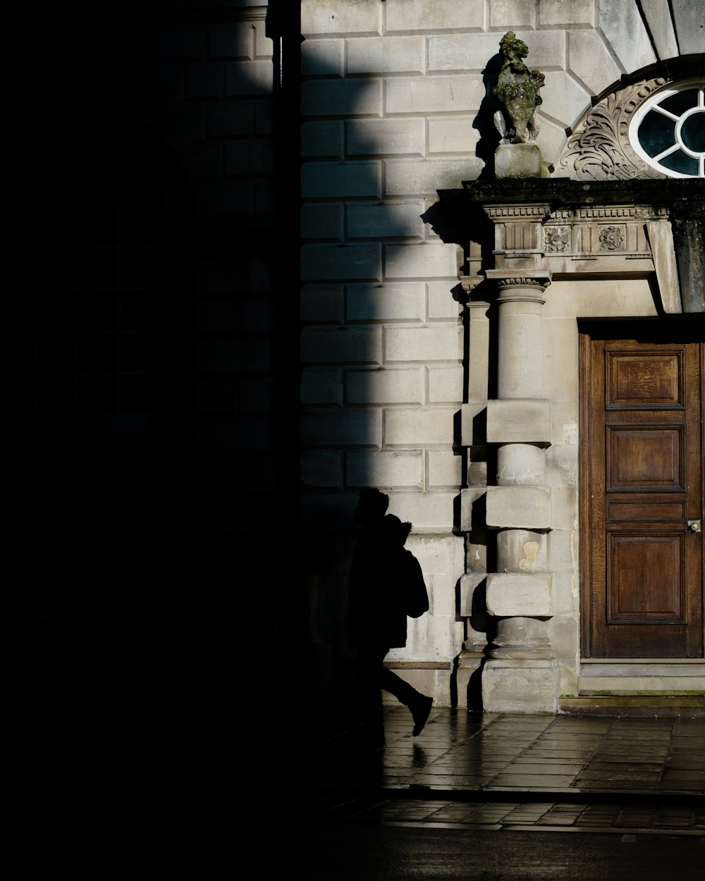 person in black coat standing near brown wooden door