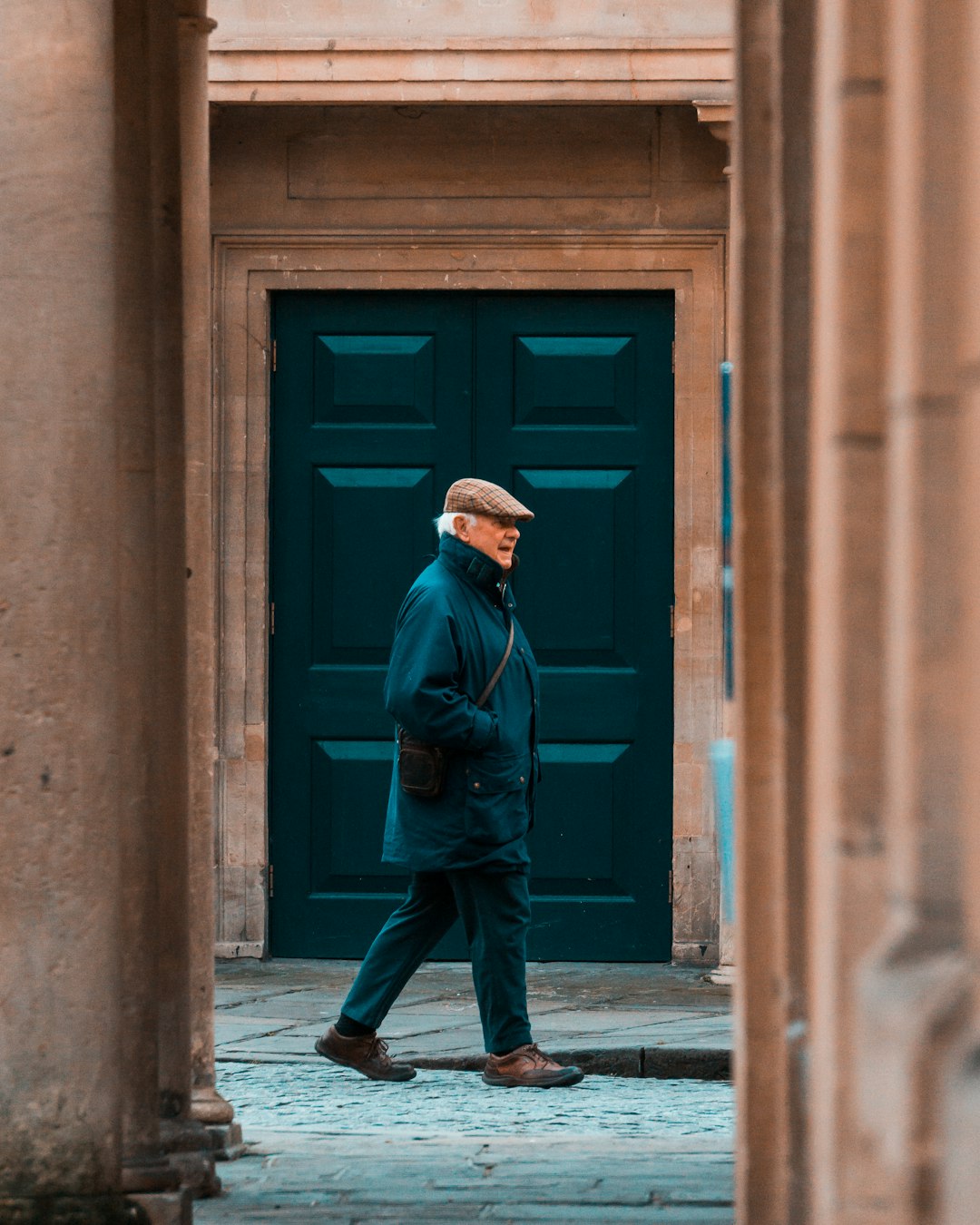 man in blue jacket and blue denim jeans standing in front of blue wooden door