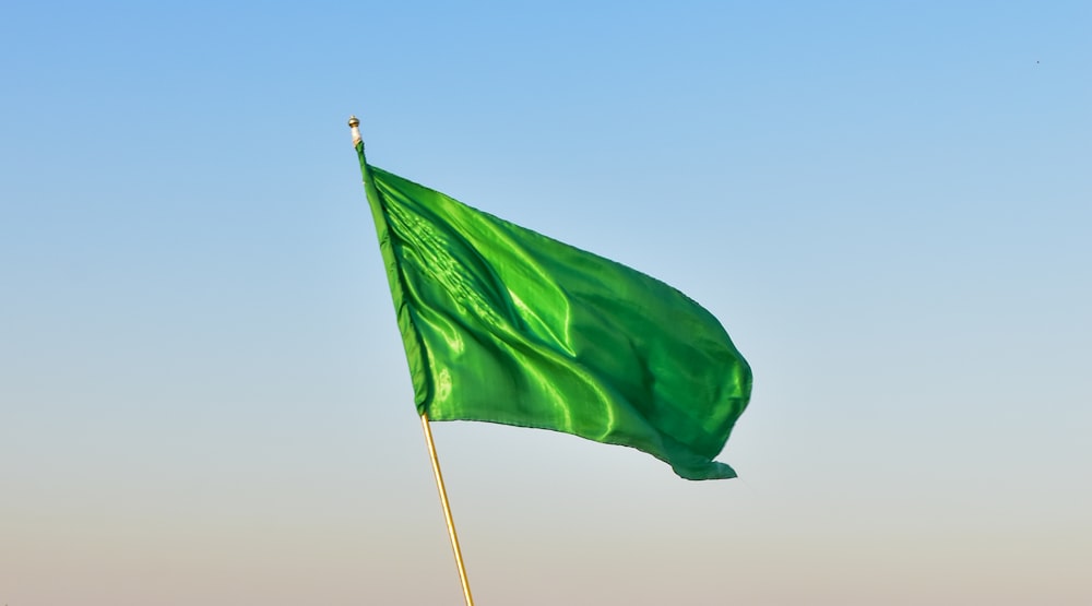 green flag on pole under blue sky during daytime