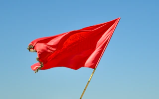 red flag on pole under blue sky during daytime