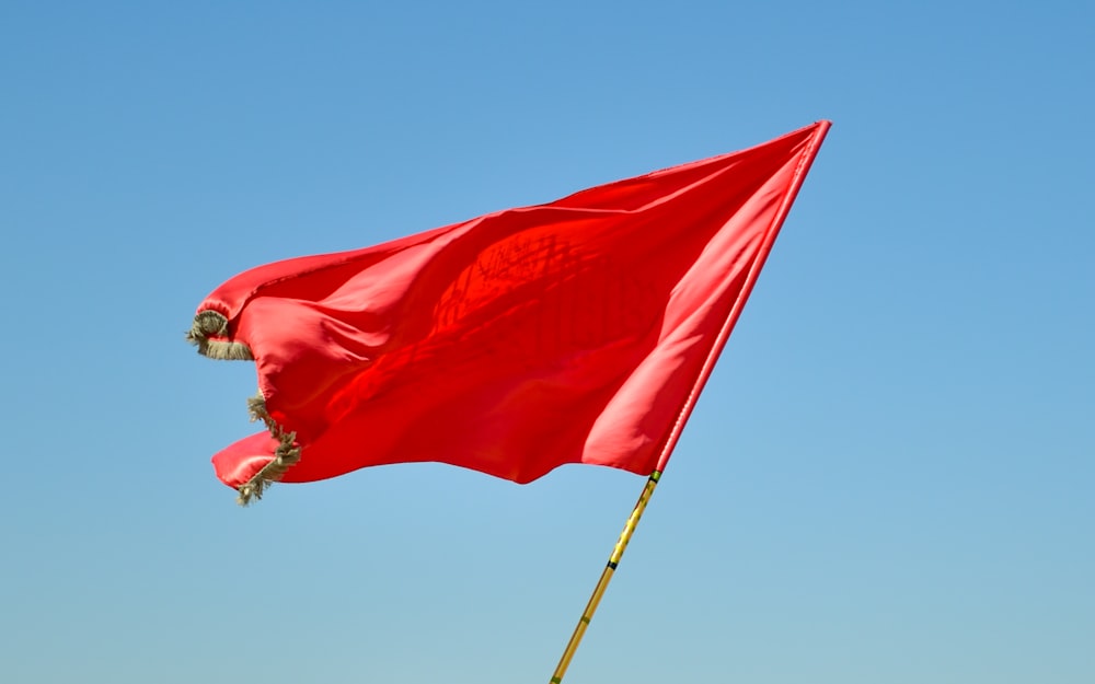 bandera roja en el poste bajo un cielo azul durante el día