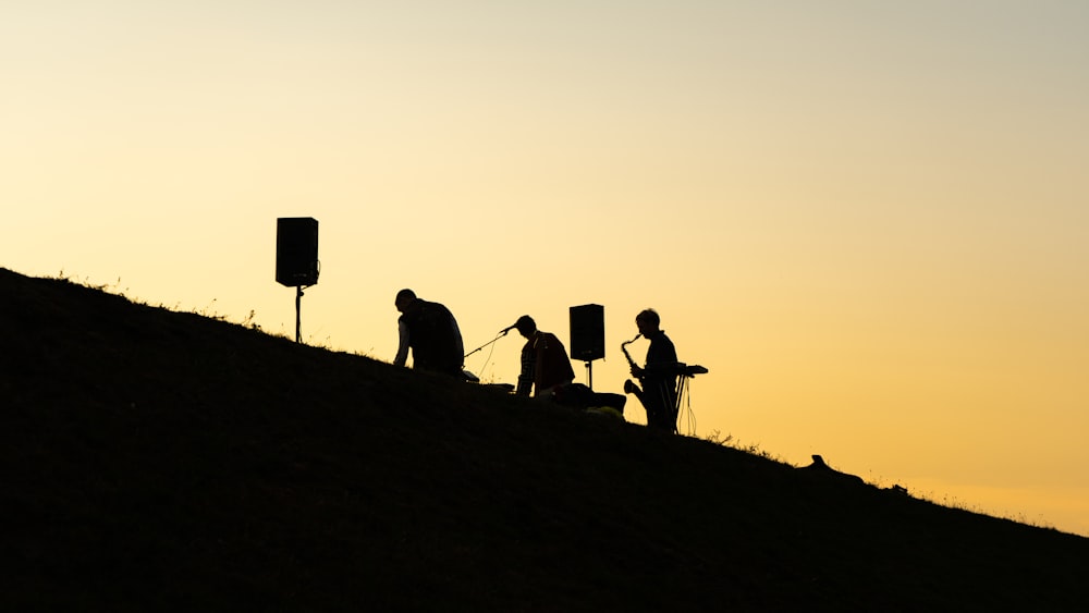 silhouette of people standing on hill during sunset