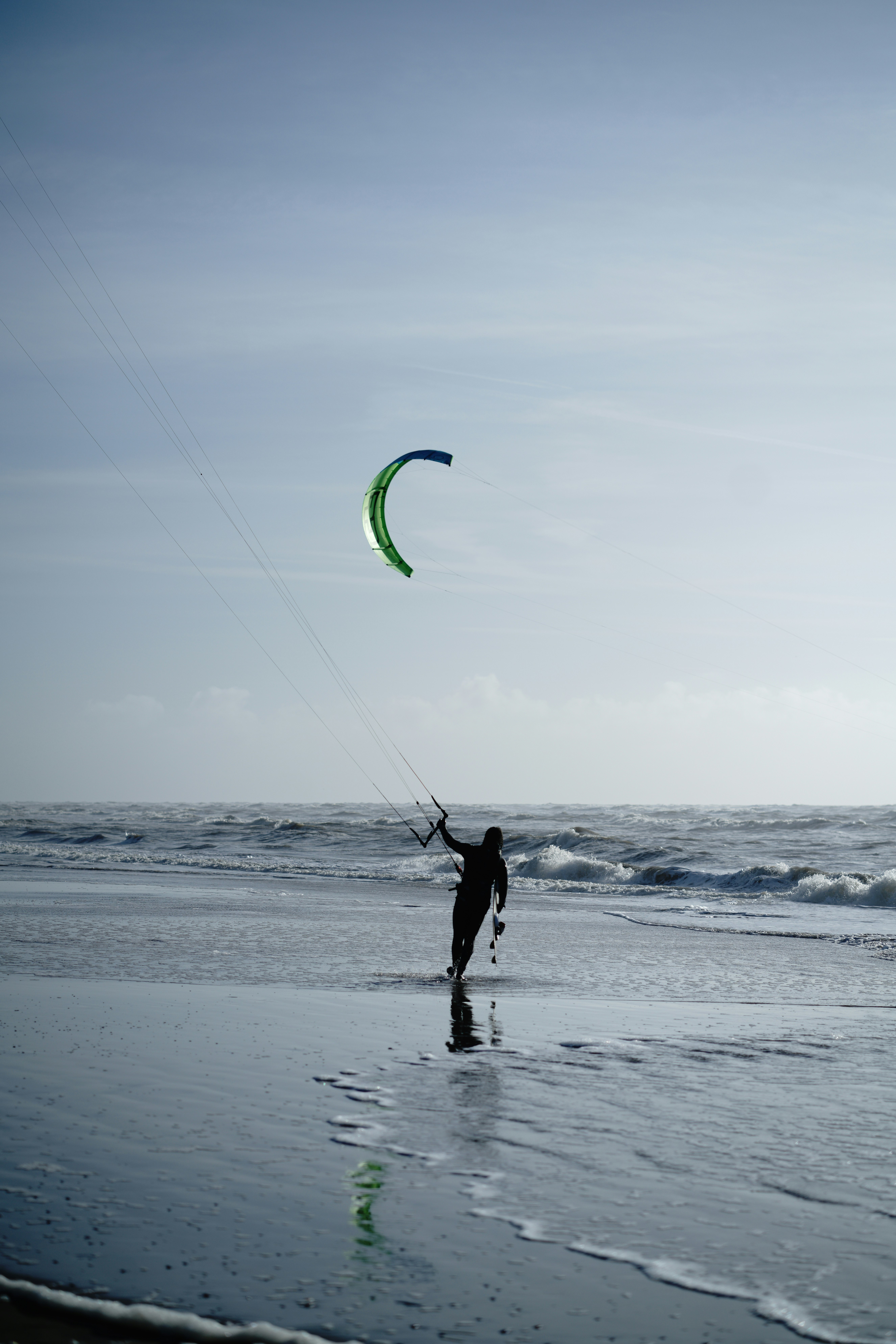 silhouette of man holding kite surfing on sea during daytime