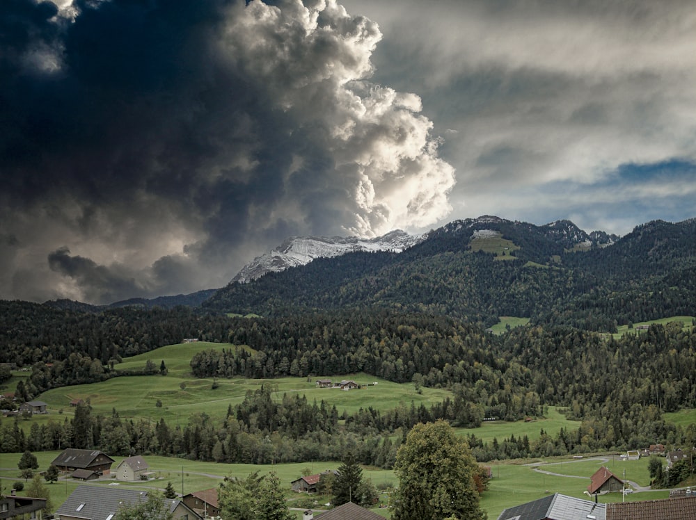 campo de hierba verde cerca de la montaña verde bajo nubes blancas y cielo azul durante el día