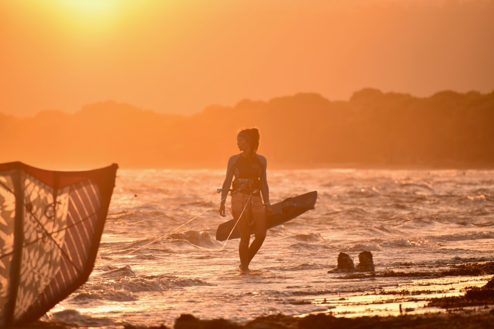 man in black shorts holding surfboard on beach during sunset