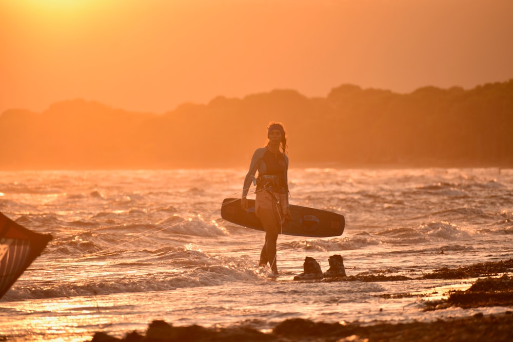 silhouette of man holding surfboard on beach during sunset