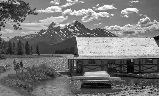 grayscale photo of a lake near a snow covered mountain in Maligne Lake Canada