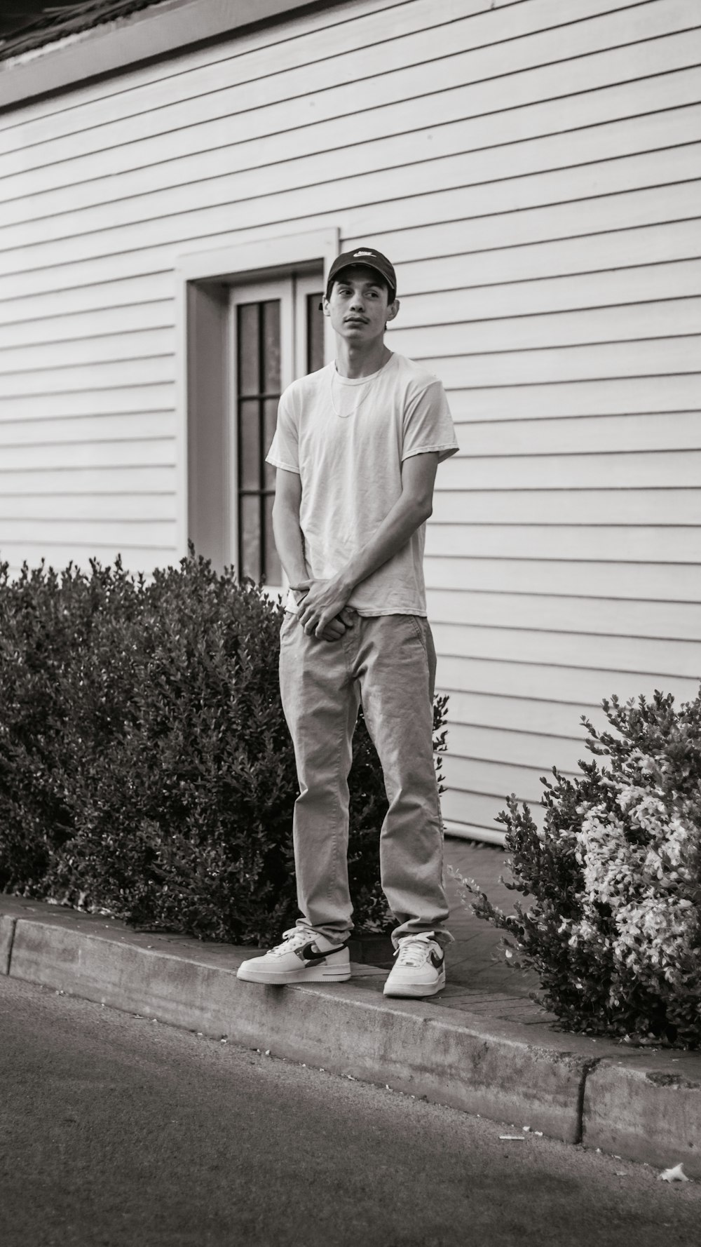 man in white crew neck t-shirt and gray pants standing on gray concrete stairs