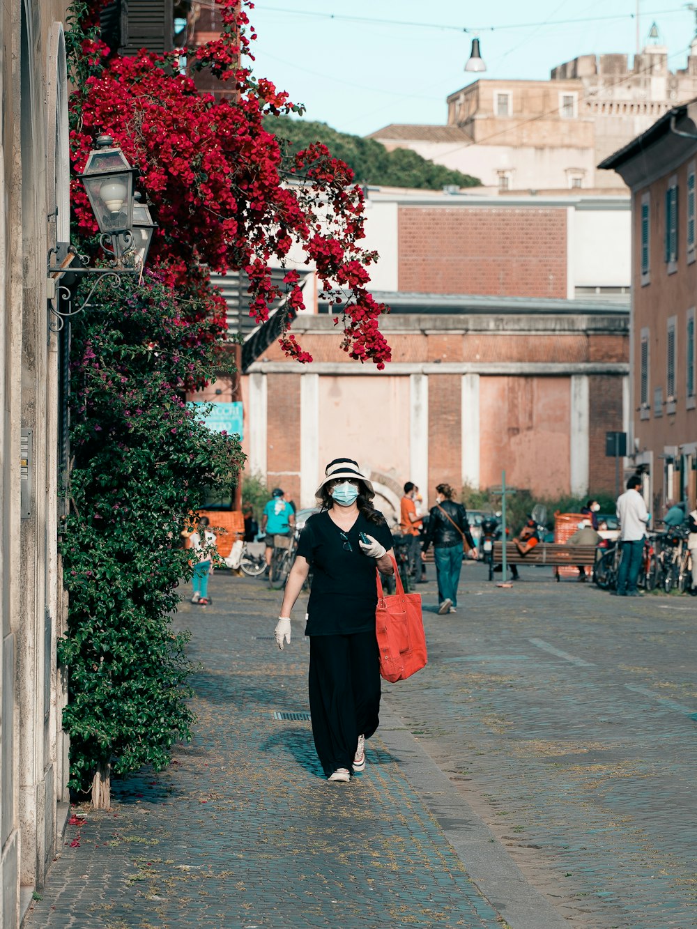 woman in black dress standing on sidewalk during daytime