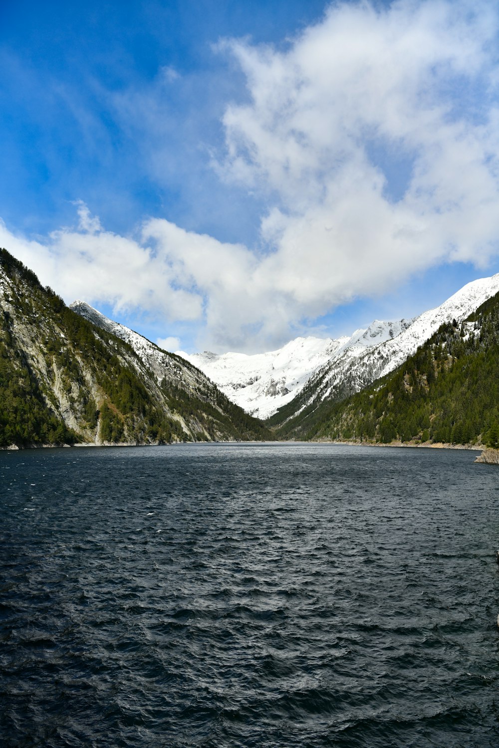 body of water near mountain under blue sky during daytime