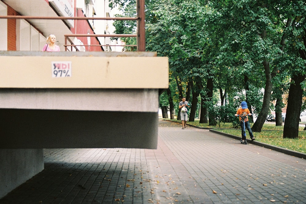 people walking on sidewalk near green trees during daytime