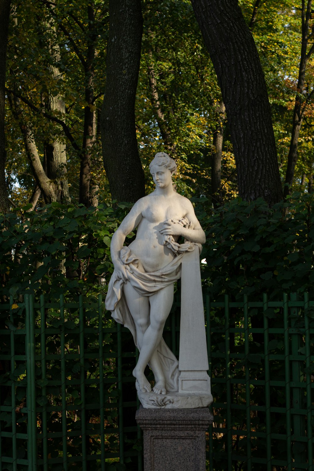 white concrete statue near green trees during daytime