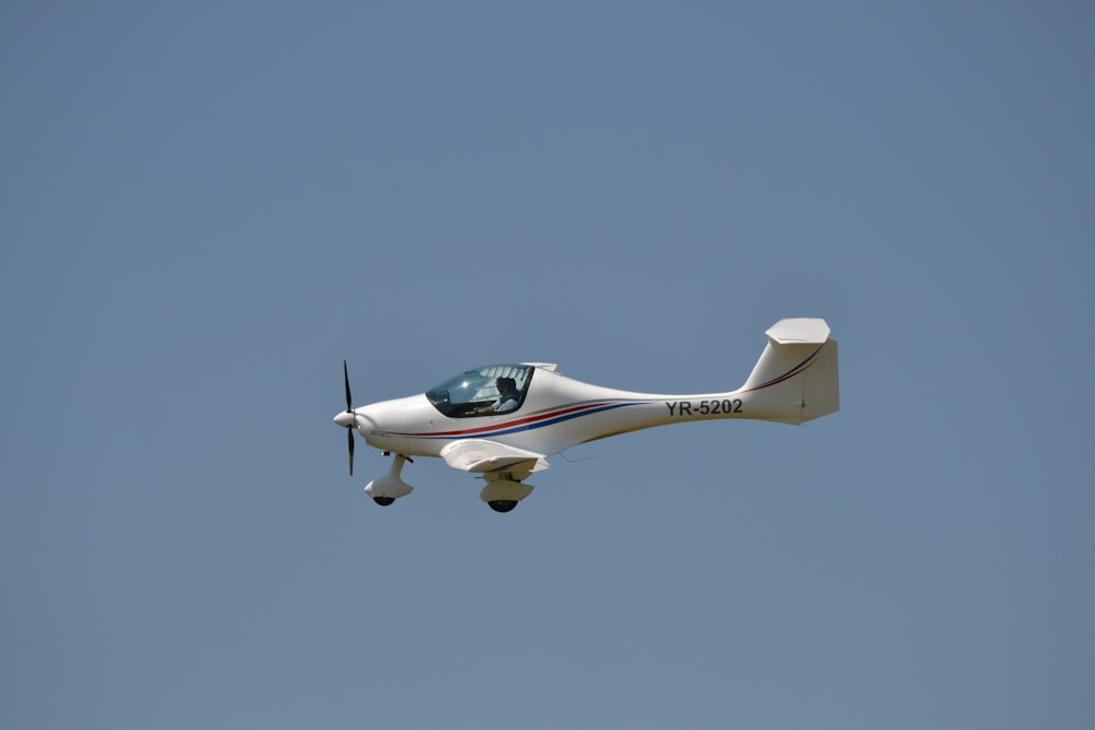 Weißes und grünes Flugzeug fliegt am Himmel