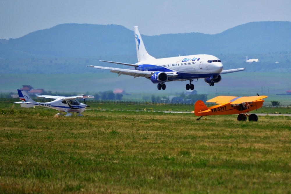 weiß-orangefarbenes Flugzeug tagsüber auf grünem Rasenfeld