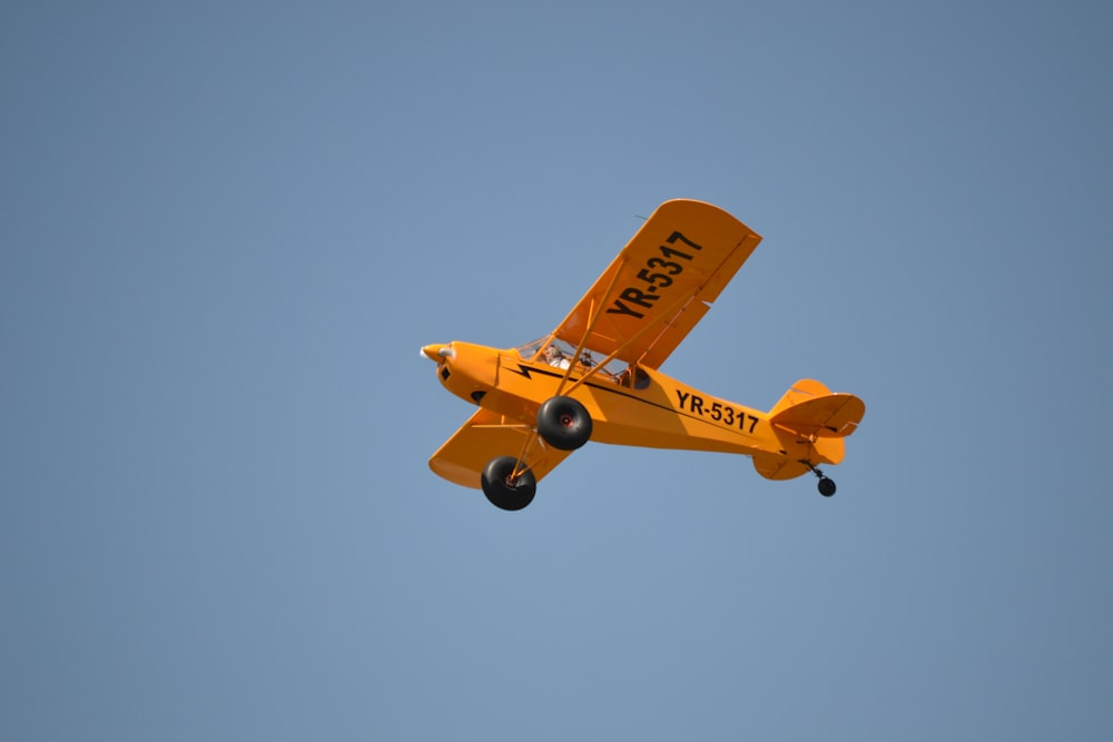 Gelbes und braunes Flugzeug fliegt am Himmel