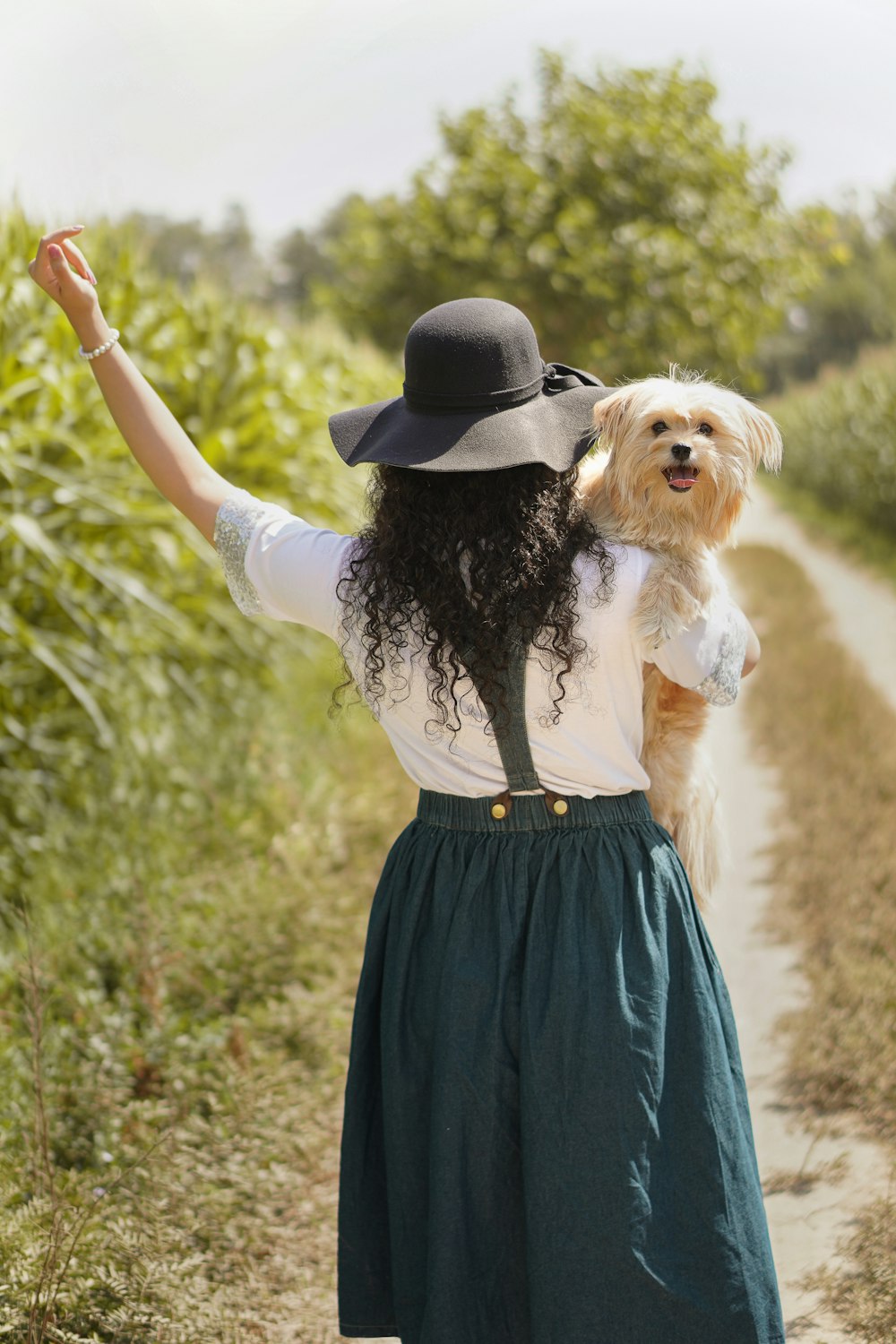 woman in white and blue dress holding brown long coated dog