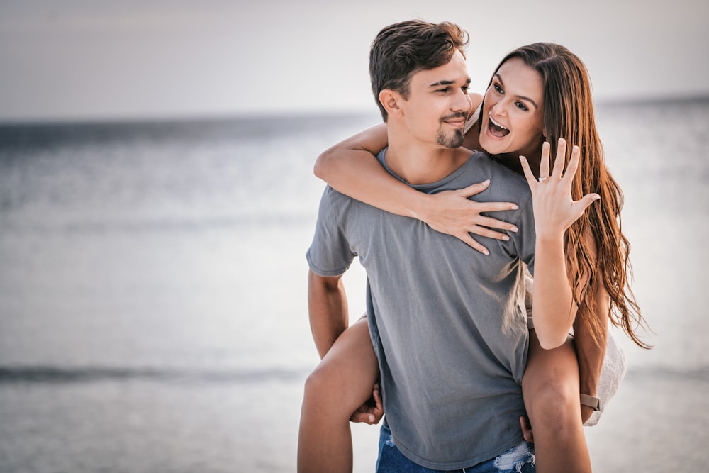 homem na camiseta branca do pescoço da tripulação abraçando a mulher em shorts jeans azuis