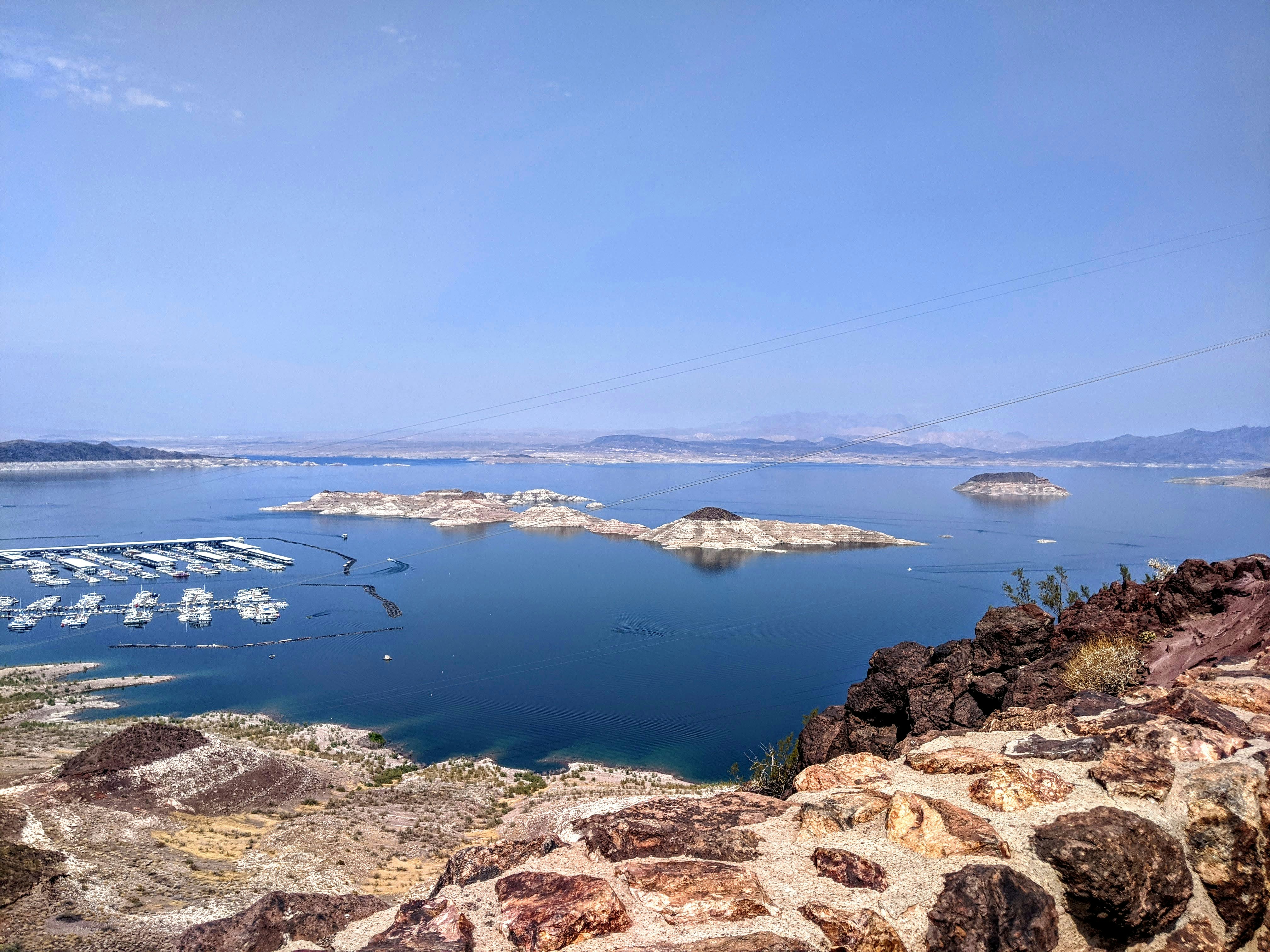 日中の青空の下、茶色のロッキー山脈近くの水域