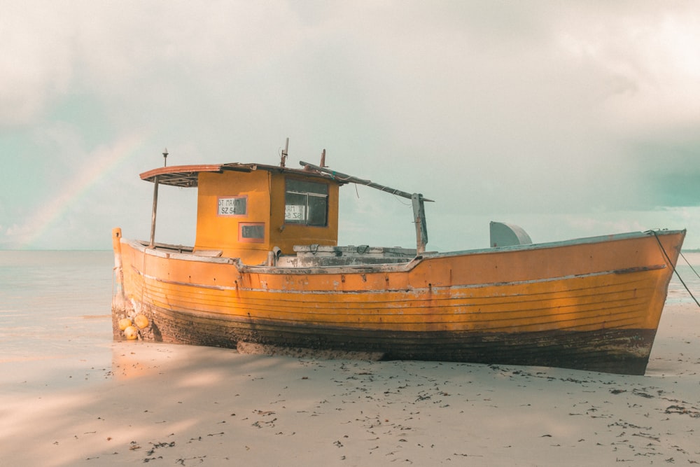 brown and white boat on brown sand during daytime