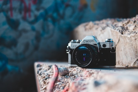 Close-up of hands holding a vintage camera capturing details inside a forgotten, graffiti-covered room.