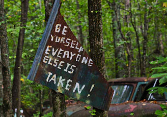 brown wooden signage near green trees during daytime