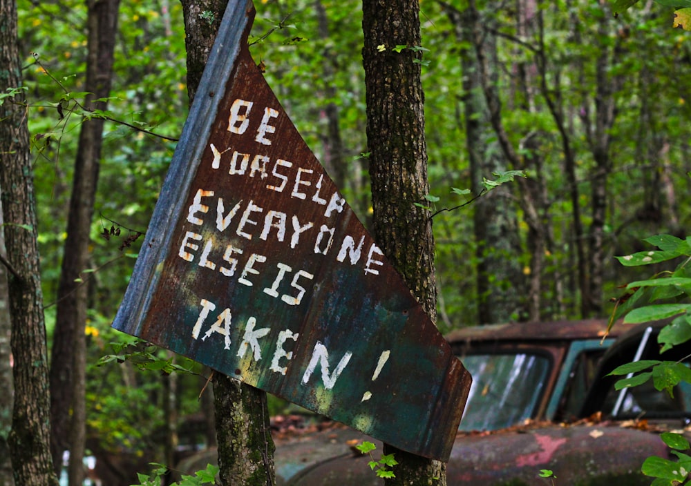 Signalisation en bois brun près des arbres verts pendant la journée