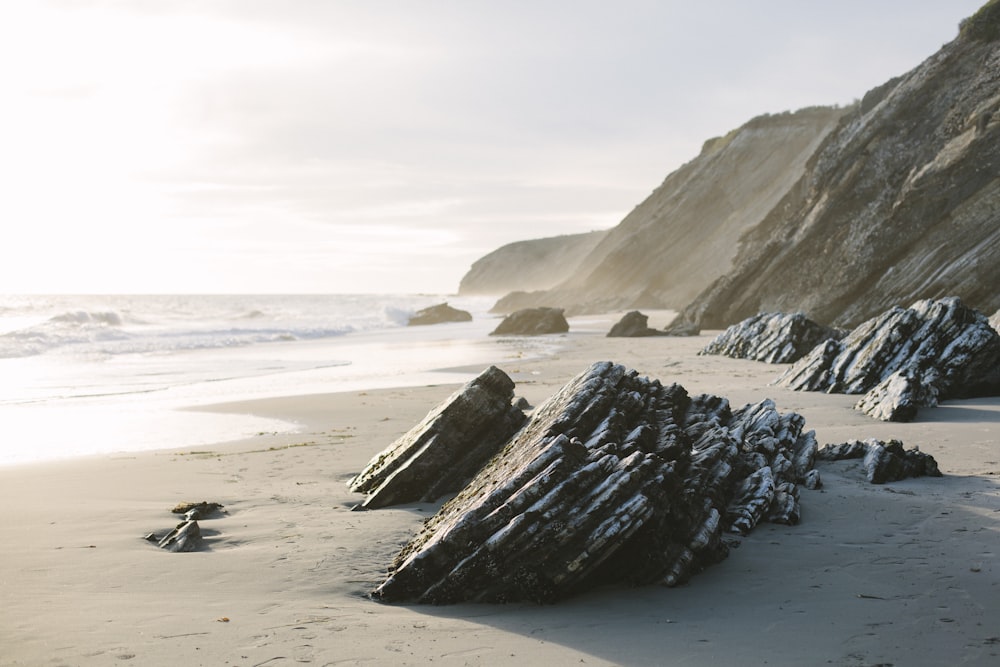 brown rock formation on white sand beach during daytime