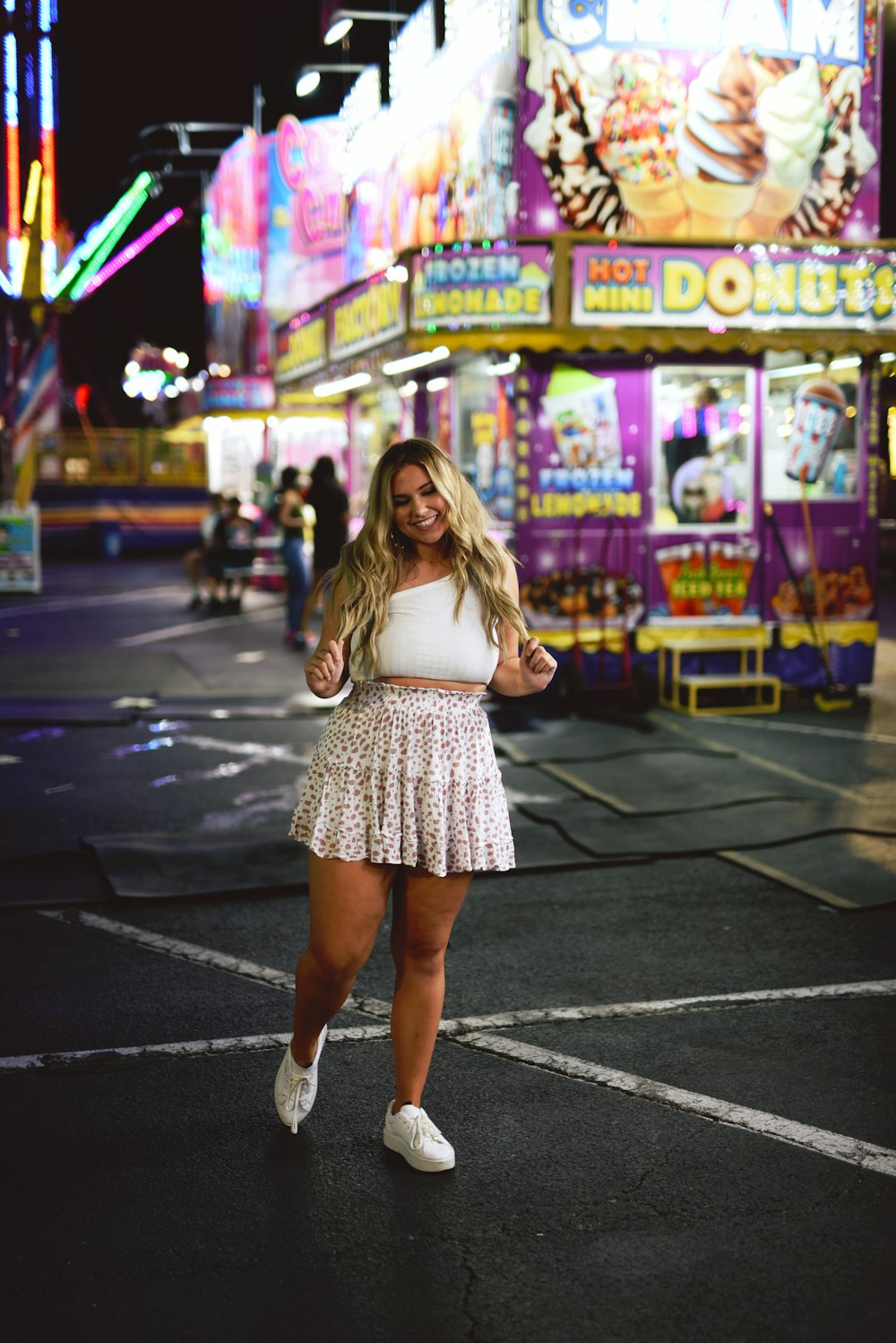 mulher no vestido branco que anda na faixa de pedestres durante a noite