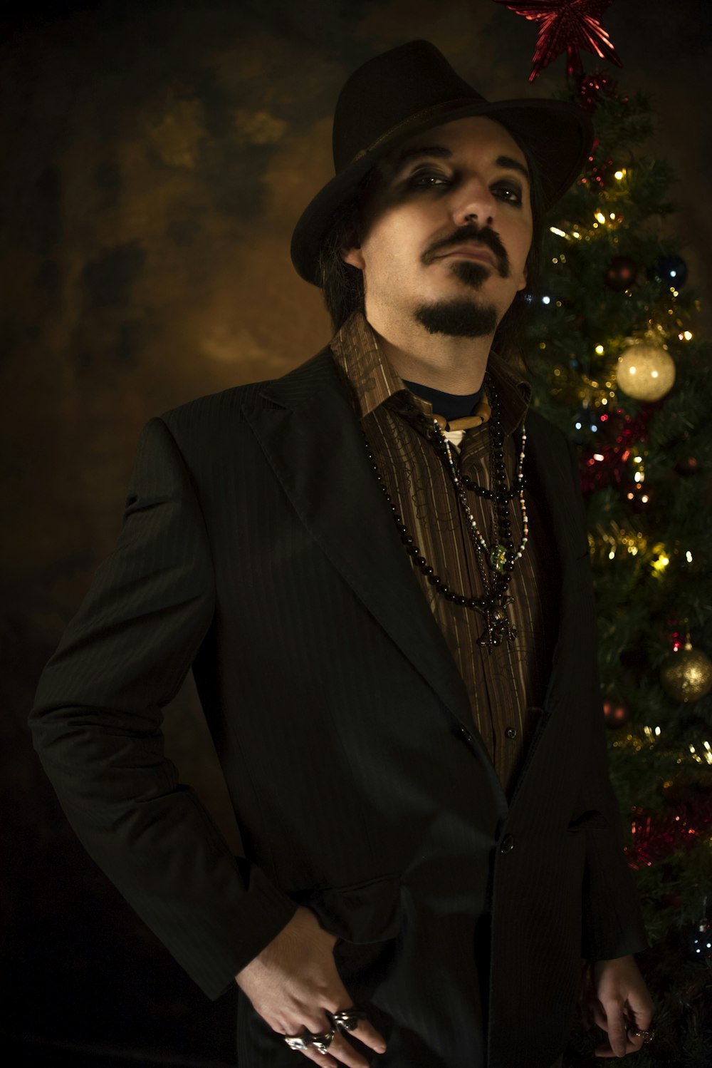 man in black suit jacket standing near christmas tree