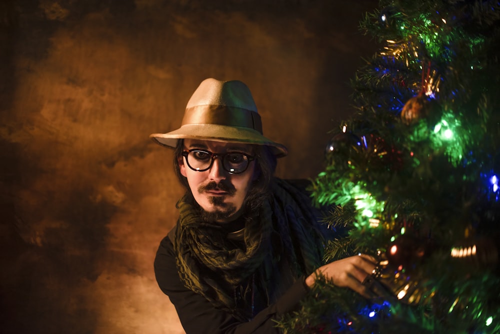 woman in brown hat and brown shirt standing beside green christmas tree