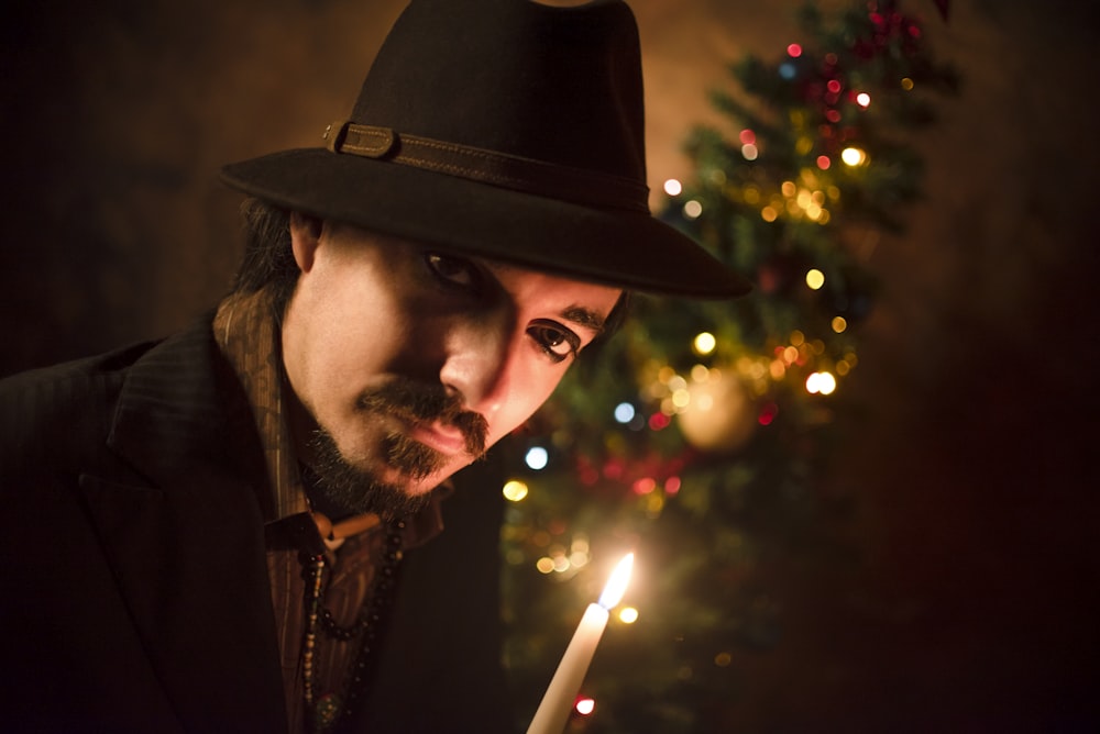 man in brown hat holding lighted sparkler