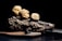 Three large truffles are artfully arranged on a piece of textured wood placed on a surface. The background is dark, highlighting the earthy tones of the truffles and the wood.