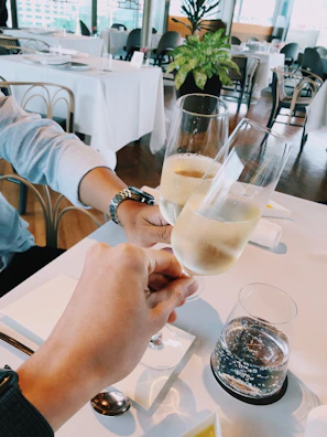 Guests laughing and clinking glasses during a wedding reception with subtle white minimalist decor.