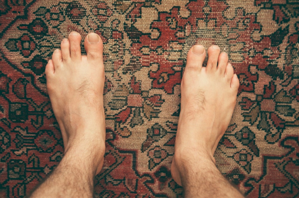 persons feet on red and brown area rug