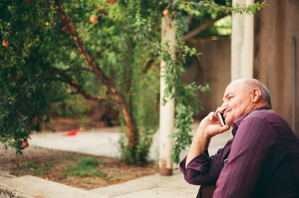 man in black jacket sitting on brown concrete bench during daytime